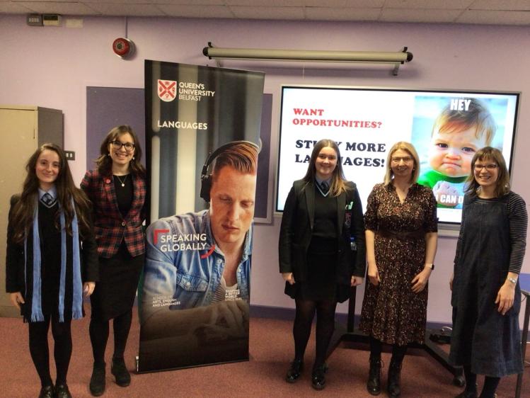 Dr Síobhra Aiken (Irish) and Dr Tori Holmes (Portuguese) standing beside a display stand with Nikol and Emma representing students from Portadown College, St Roman's and Lurgan College, and Dr Christine Le Sann.